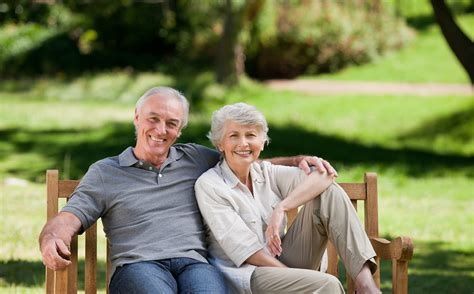 A man and woman sitting on top of a wooden bench.