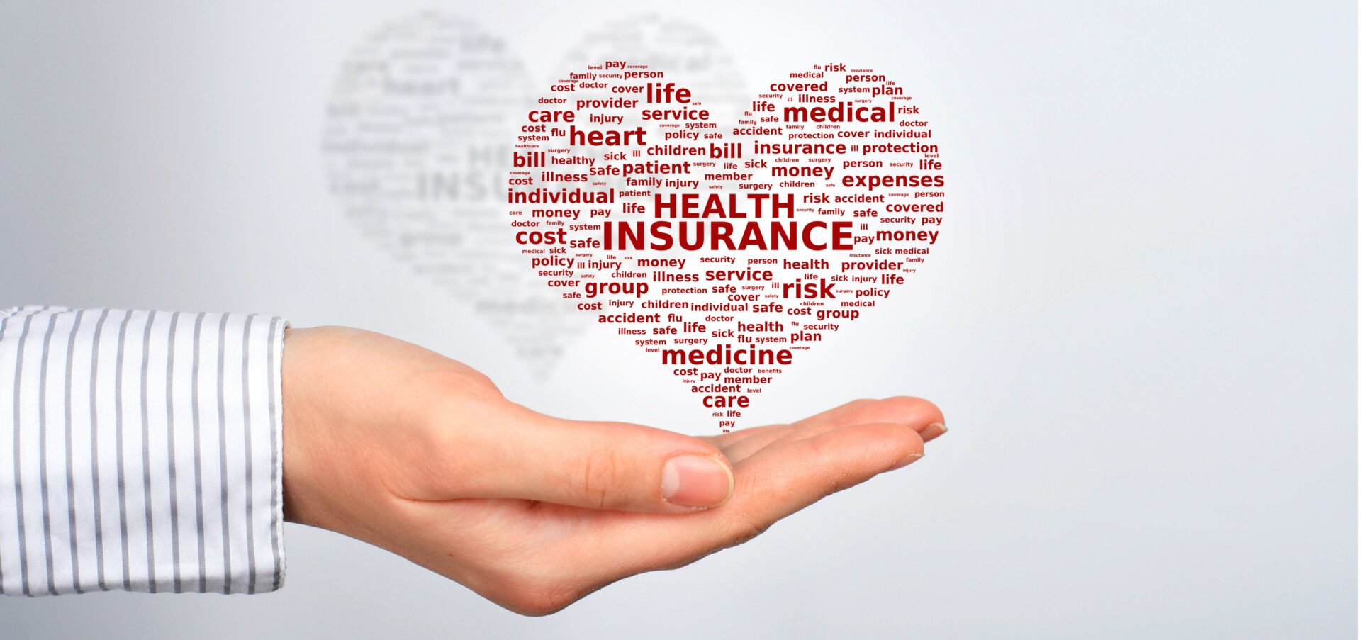A hand holding a heart-shaped word cloud with health insurance terms.